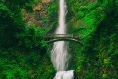 Tall waterfall with bridge above