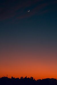 Fiery sunset with crescent moon Crescent moon and fiery orange sunset horizon
